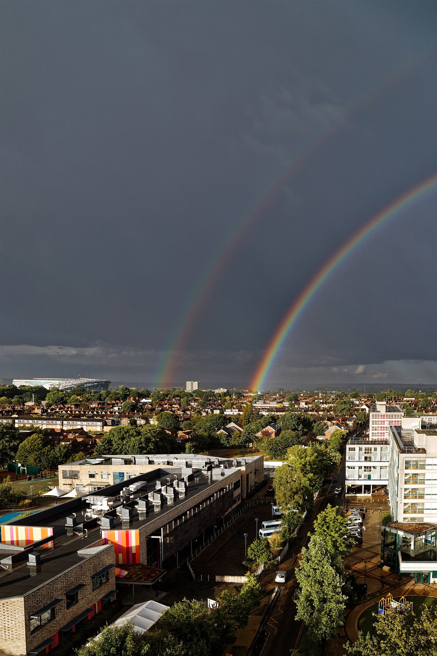 Een regenboog verschijnt wanneer zonlicht regendruppels bereikt; zon en buien kunnen tegelijk zichtbaar zijn.